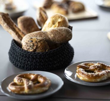 Frische Brötchen und Brezn auf Tellern, serviert im MeetingRAUM Ingolstadt als Teil des regionalen Frühstücksangebots.