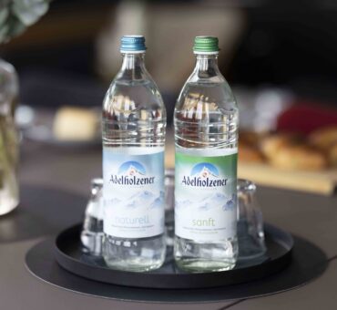 Zwei Flaschen Adelholzener Mineralwasser mit Gläsern auf einem schwarzen Tablett – bereitgestellt im MeetingRAUM Ingolstadt.