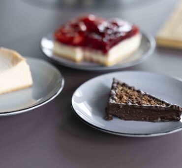Drei verschiedene Kuchensorten – Käsekuchen, Schokoladenkuchen und Fruchtkuchen – auf grauen Tellern serviert im MeetingRAUM Ingolstadt.