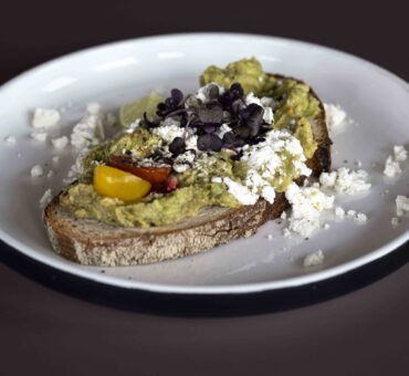 Joghurt mit Müsli und Obst sowie Avocado-Brot mit Feta und Kernen auf einem Tisch – Teil des gesunden Frühstücks im MeetingRAUM Ingolstadt.