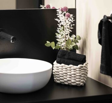 Waschbecken mit schwarzer Armatur, Handtuchkorb und stilvoller Blumendeko im modernen WC-Bereich des MeetingRAUM Ingolstadt.